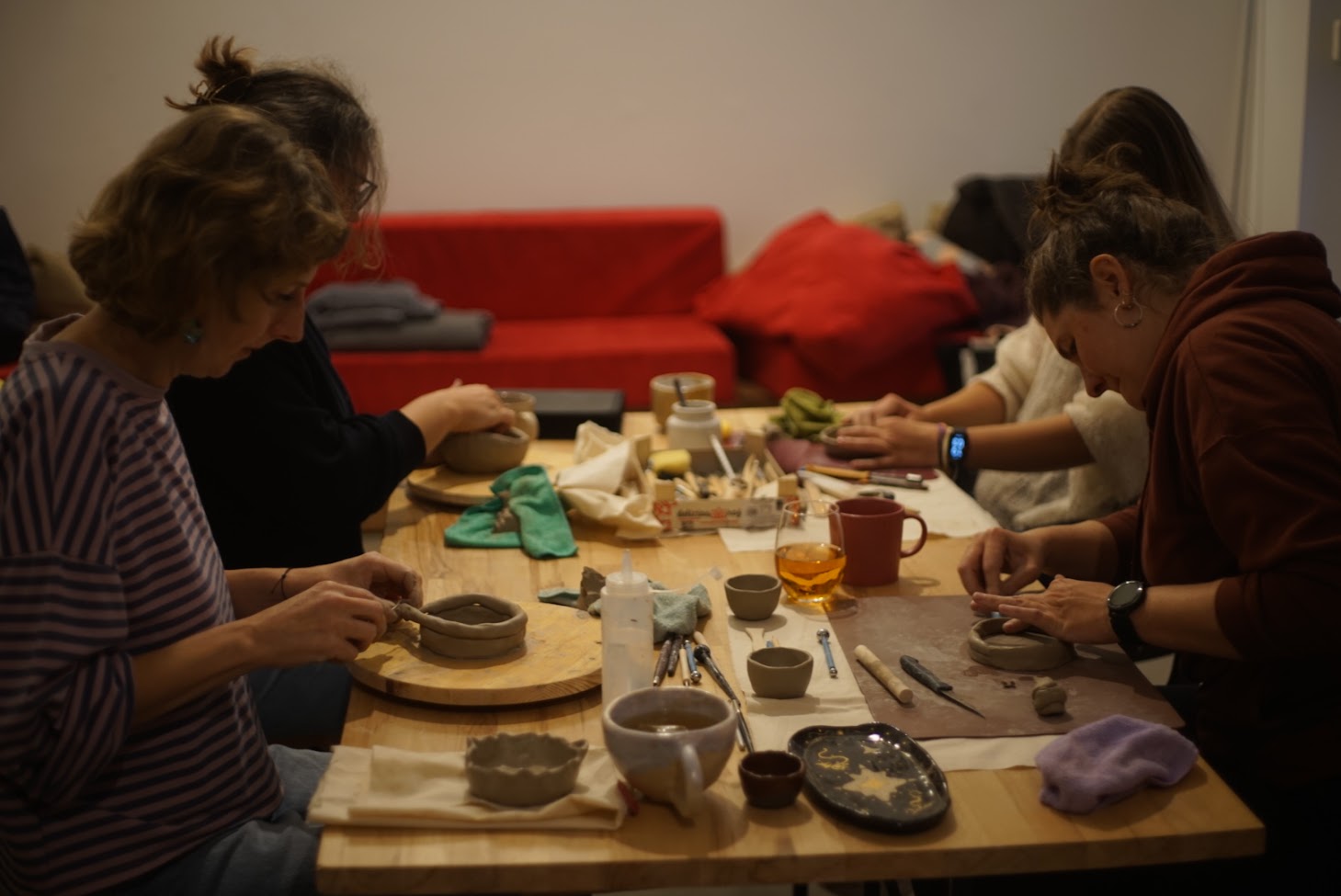 A participant forming a clay piece at the studio table