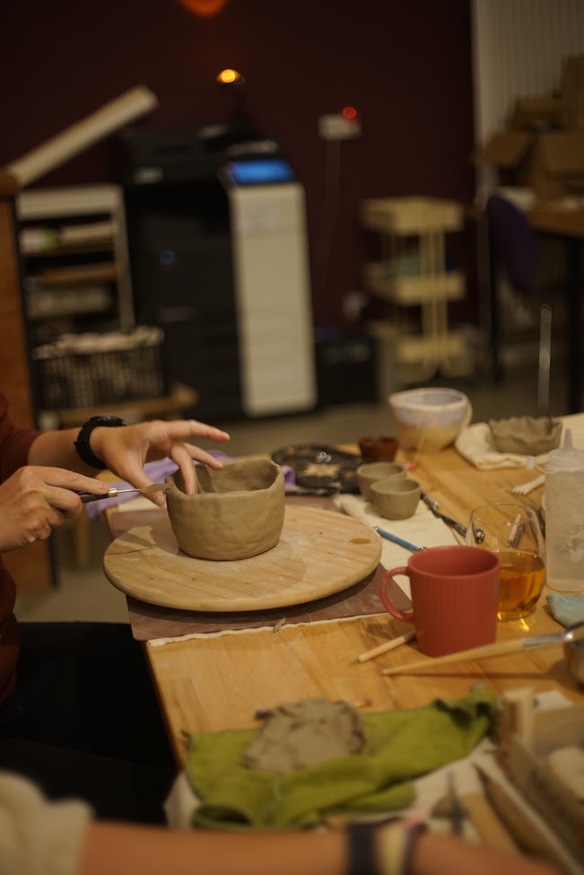 A participant smoothing out the surface of their clay work