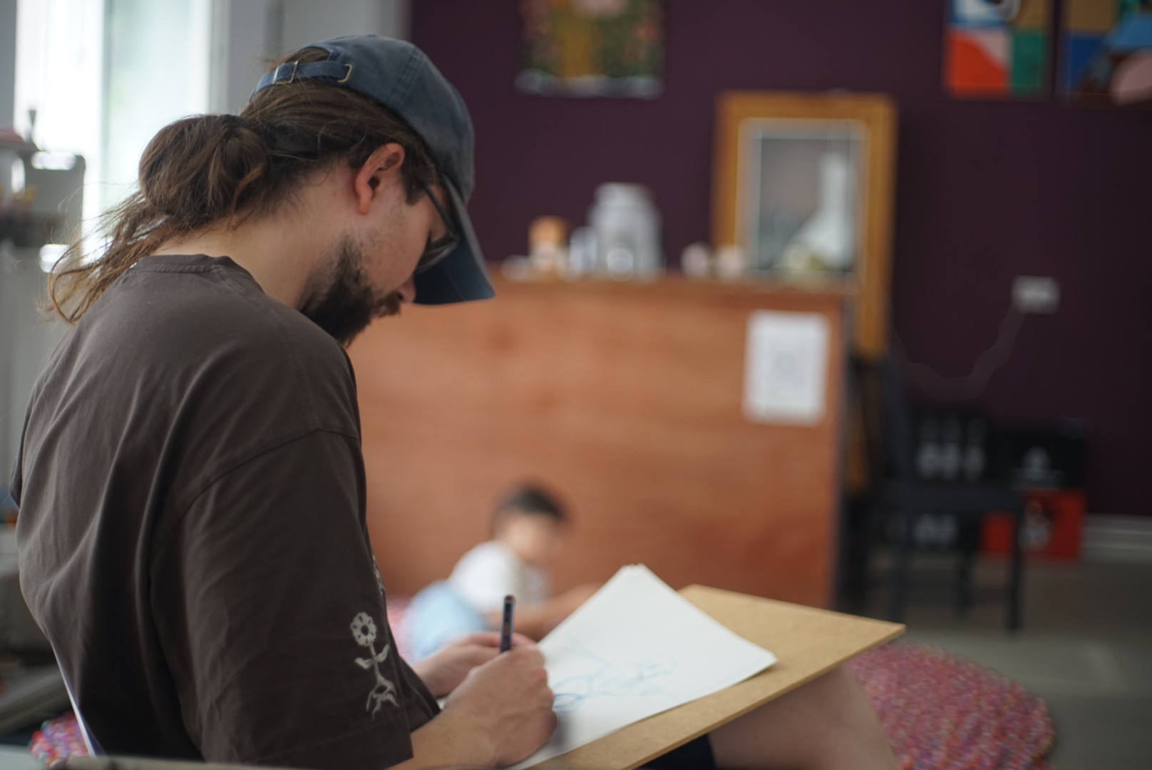 A man sketching in front of the studio's purple wall