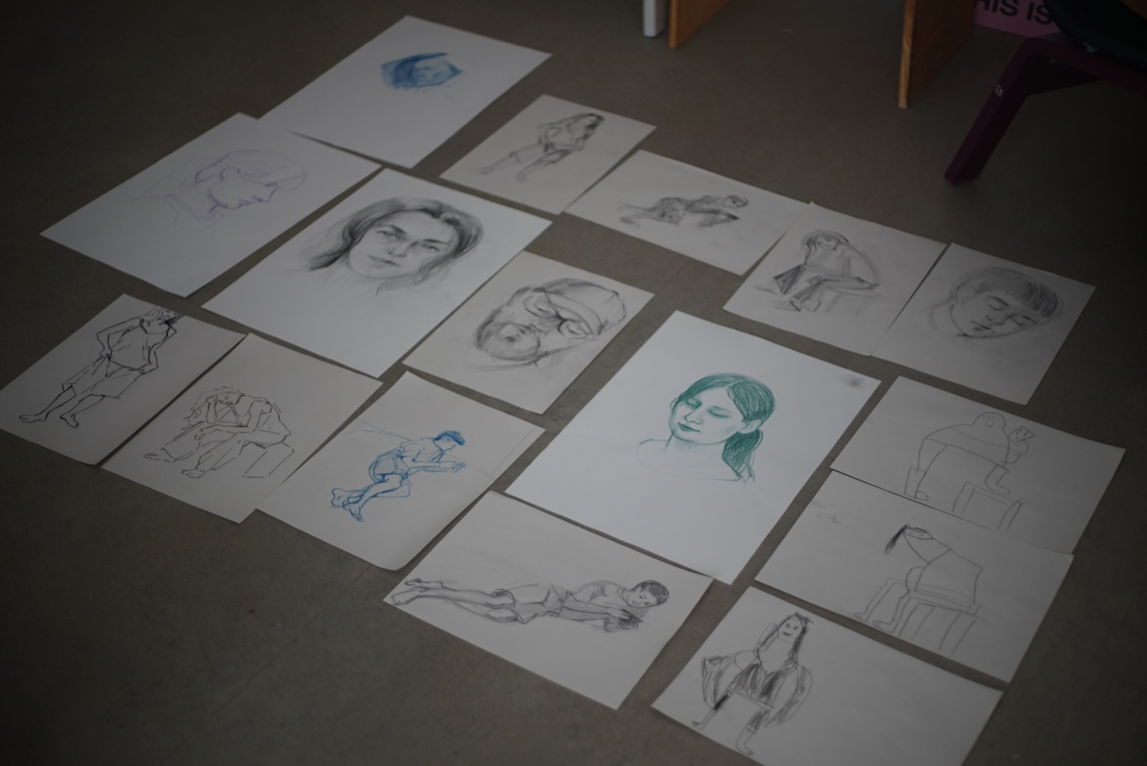 A spread of finished figure sketches laid out across the studio floor